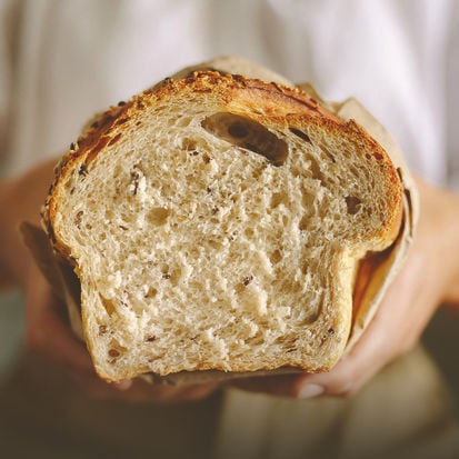 Photo of hands holding a loaf of bread